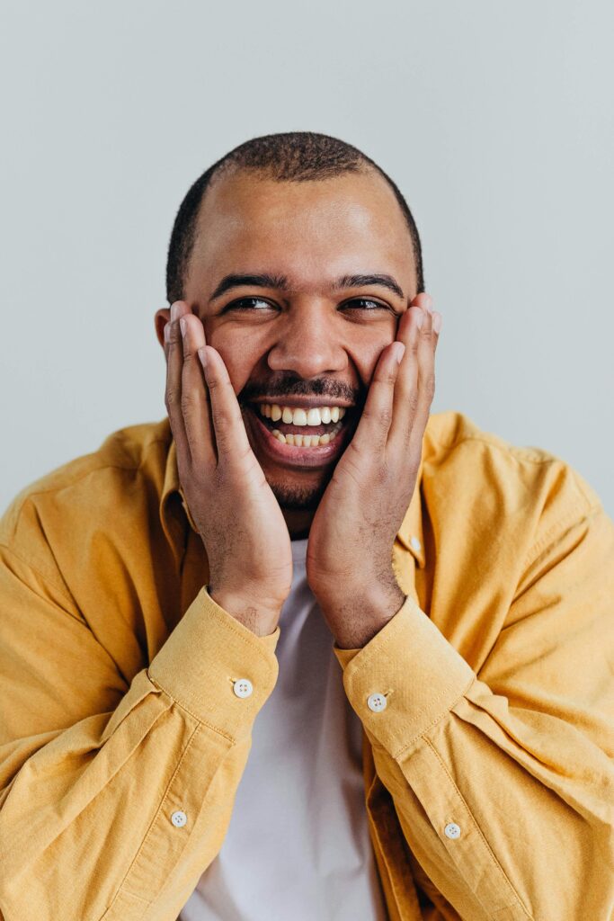 Happy African American man smiling with hands on face in studio shot.