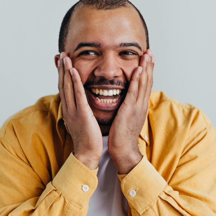 Home Happy African American man smiling with hands on face in studio shot.
